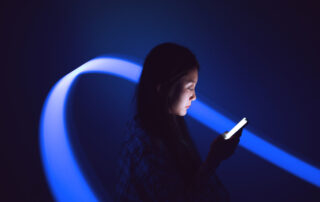 A woman looking at the bright light from her phone in a dark room