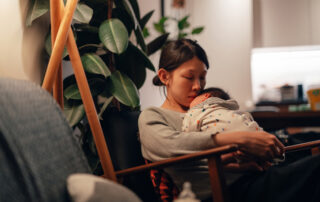 A mother looking dispondent holding her new born baby to her chest
