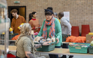 A group of vounteers organising food donations onto tables at a food bank in England.