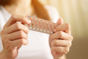 Woman hands opening birth control pills in hand.