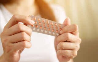Woman hands opening birth control pills in hand.