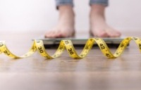 Weight Person stood on scales with a measuring tape on the floor in front