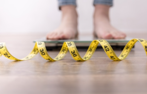 Person stood on scales with a measuring tape on the floor in front