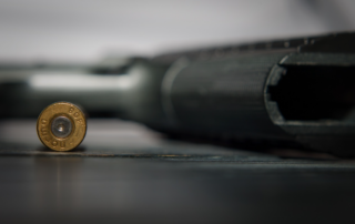 A pistol lying on a table with a bullet beside it