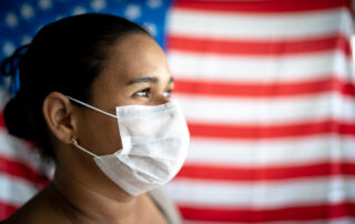 Woman wearing a face mask stood infront of the US flag