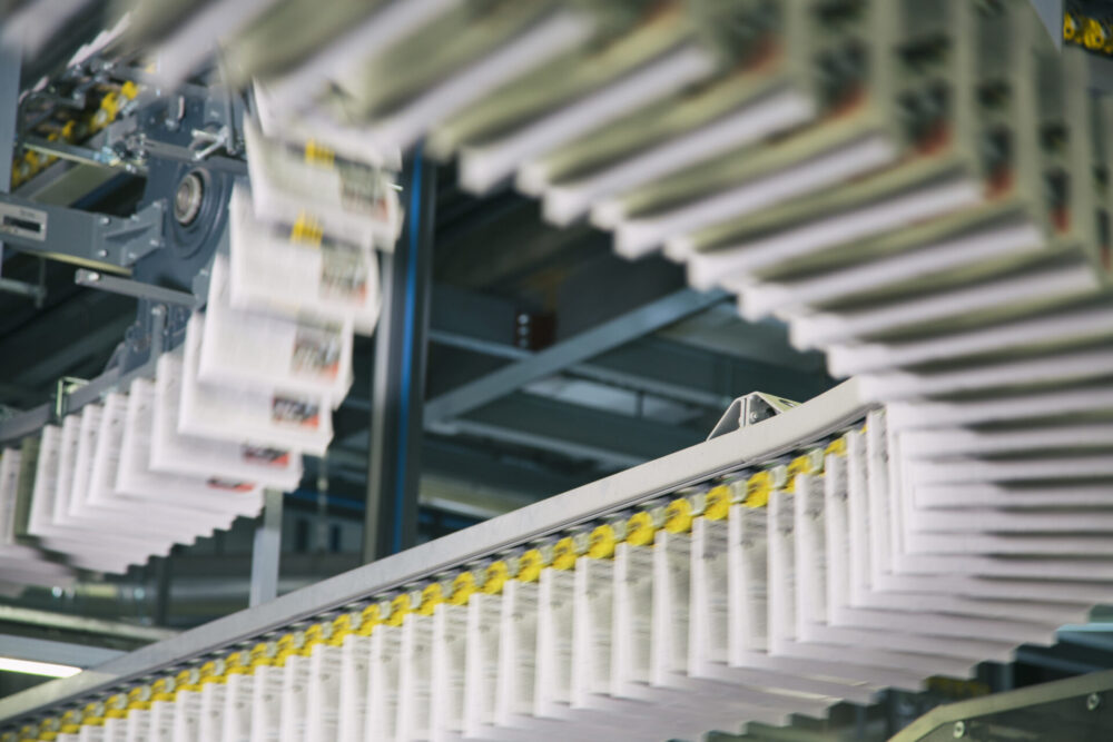 Conveyor belts with newspapers in printing press