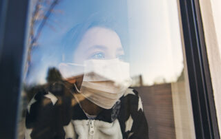 Woman in face mask looking out of a window