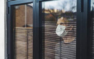 Man wearing a mask looking out of window