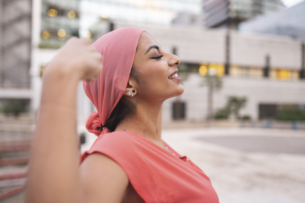pretty with pink cancer scarf woman with raised arms showing muscle