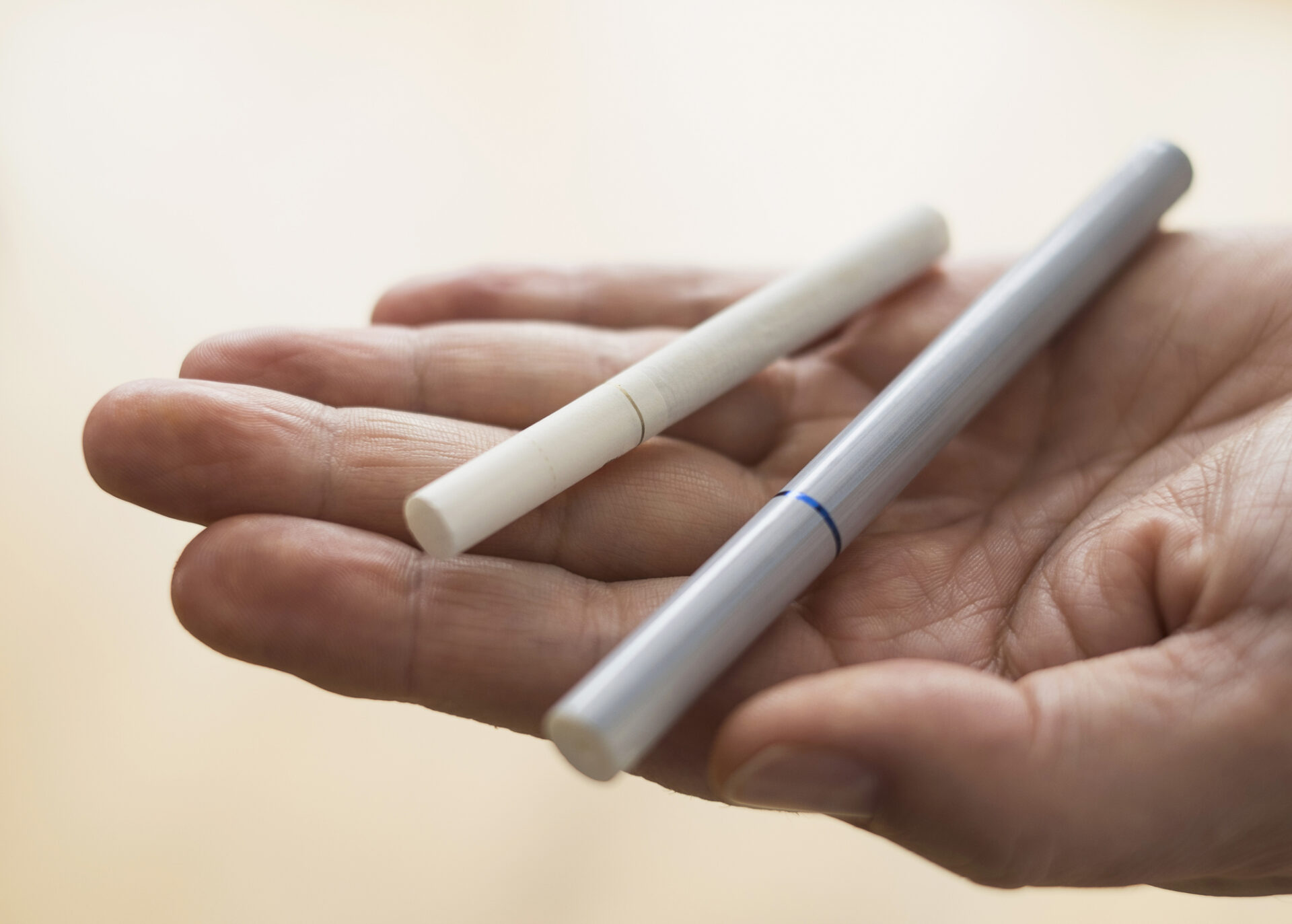 Close up of mans hand holding cigarette and e-cigarette