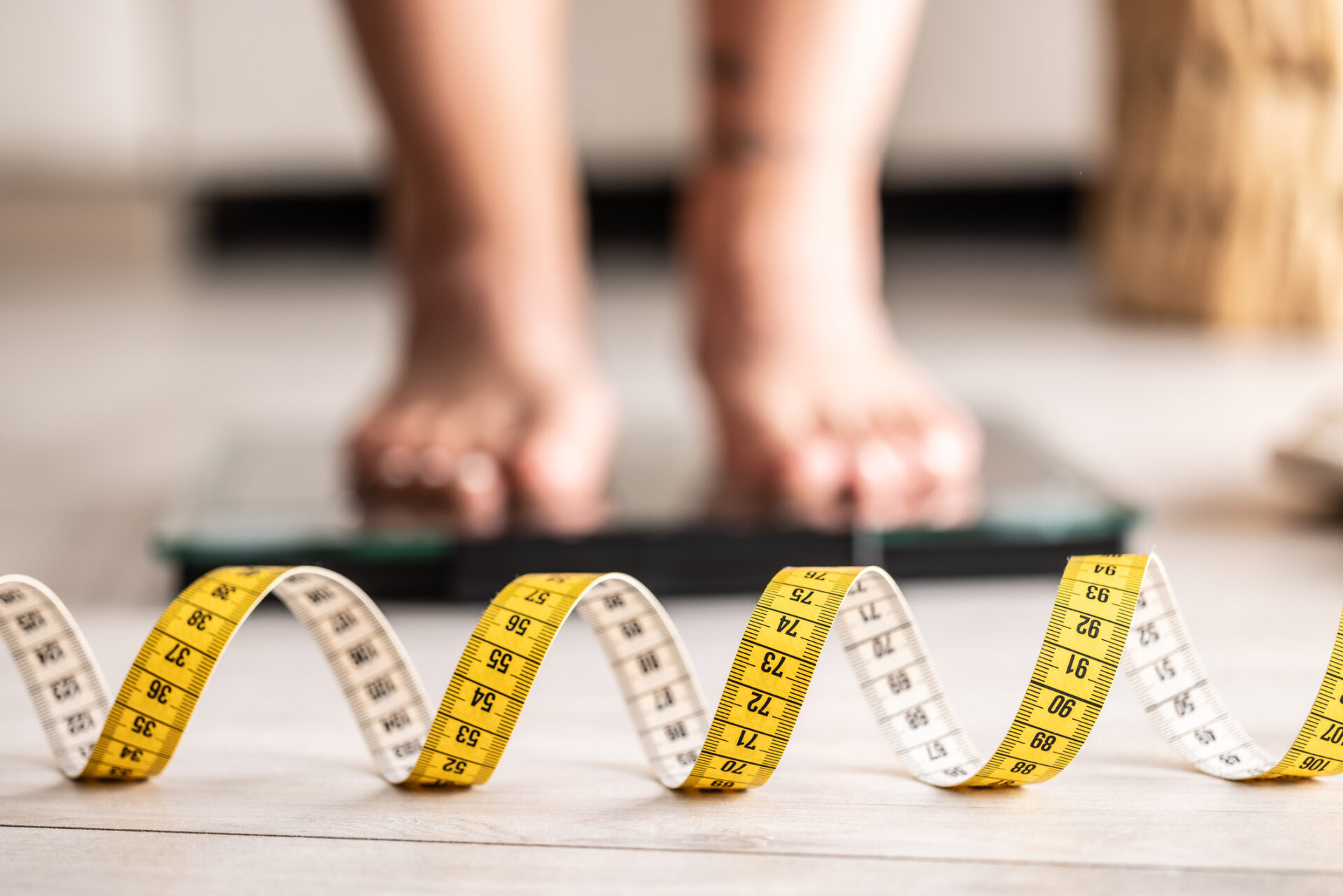 Womens legs on the scales close-up of a measuring tape the concept of losing weight healthy lifestyle