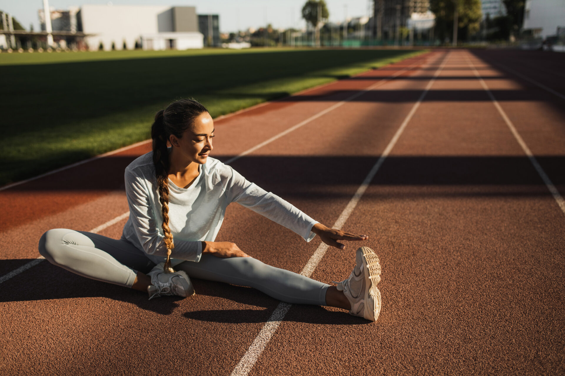 Fit multiracial woman doing stretching exercises at outdoor stadium