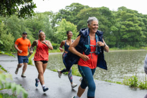 Four middle ages older people running next to a lake