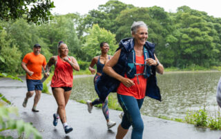 Four middle ages older people running next to a lake