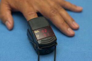 brown skinned hand with pulse oximeter on index finger