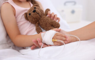 Mother and her little daughter with IV drip on bed in hospital closeup