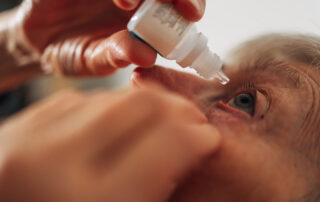 Senior adult carefully applying eye drops to her eye
