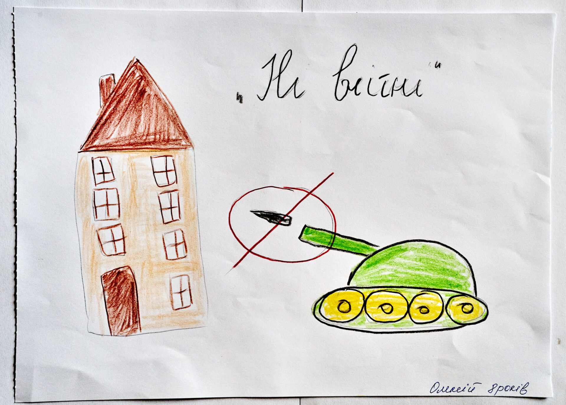 Child's drawing of a house and a tank with a cross through it. 'No War' in Ukrainian written at the top