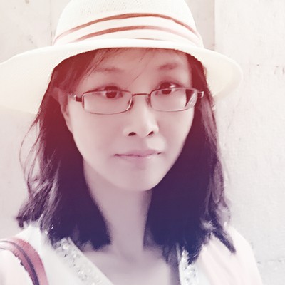 Portrait of a woman wearing a white sun hat and glasses, looking at the camera.