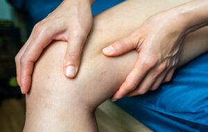 Hands kneading the knee during a leg massage or rehabilitation session