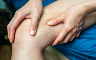 Hands kneading the knee during a leg massage or rehabilitation session