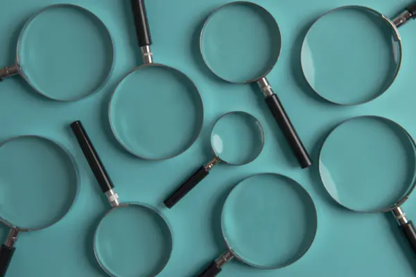 Several teal frying pans of different sizes arranged on a teal surface.
