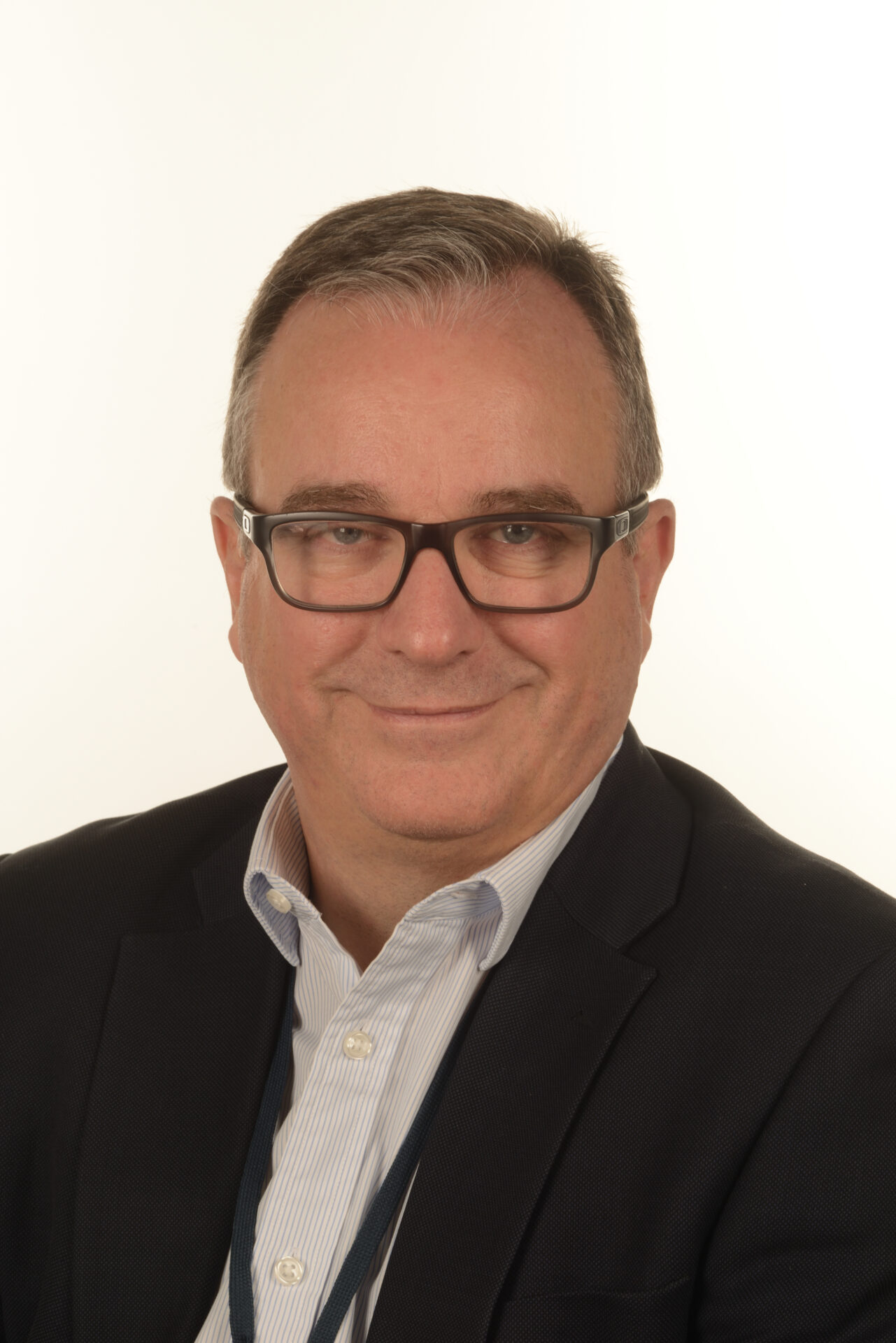 Head-and-shoulders portrait of a smiling man in glasses and a suit, looking at the camera.