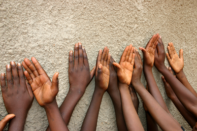 Childrens hands raised against a textured wall