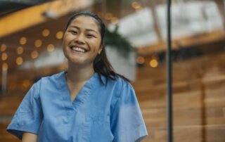 Portrait of happy young female physician in hospital seen through glass