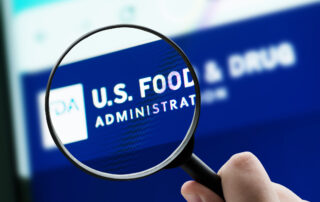 Close-up of a hand holding a magnifying glass over a blue screen reading 'U.S. FOOD ADMINISTRATION'.