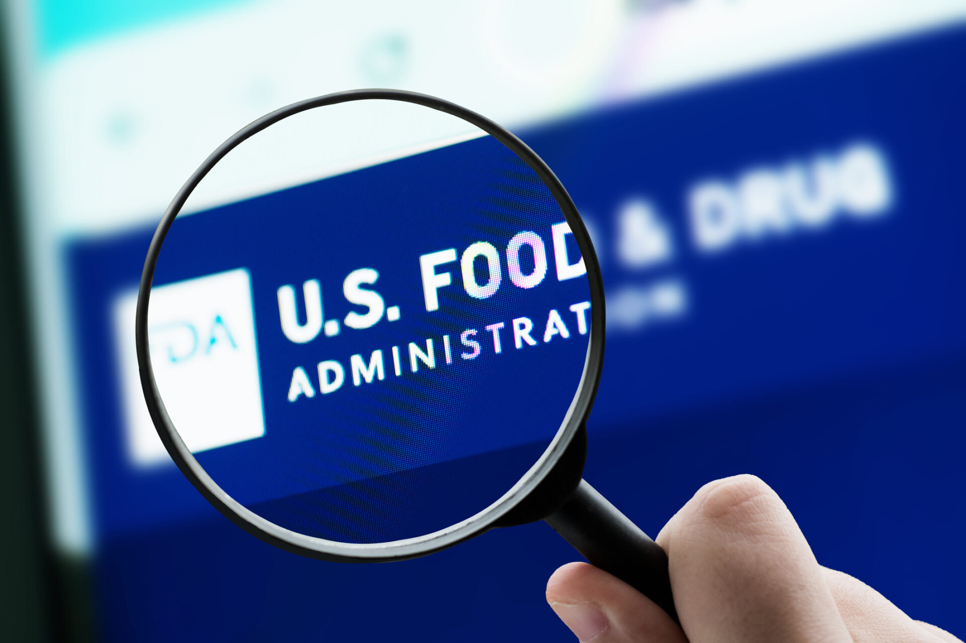 Close-up of a hand holding a magnifying glass over a blue screen reading 'U.S. FOOD ADMINISTRATION'.